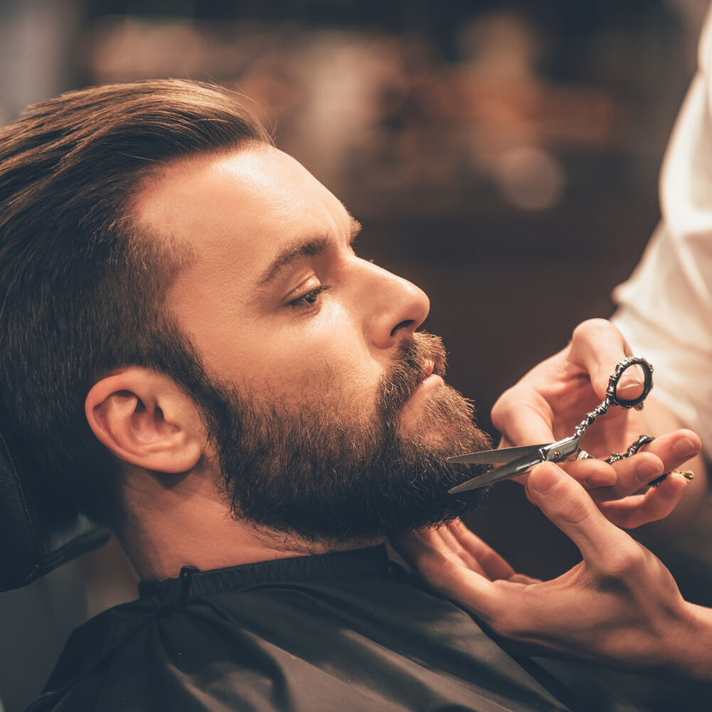 A man getting his beard trimmed by a barber